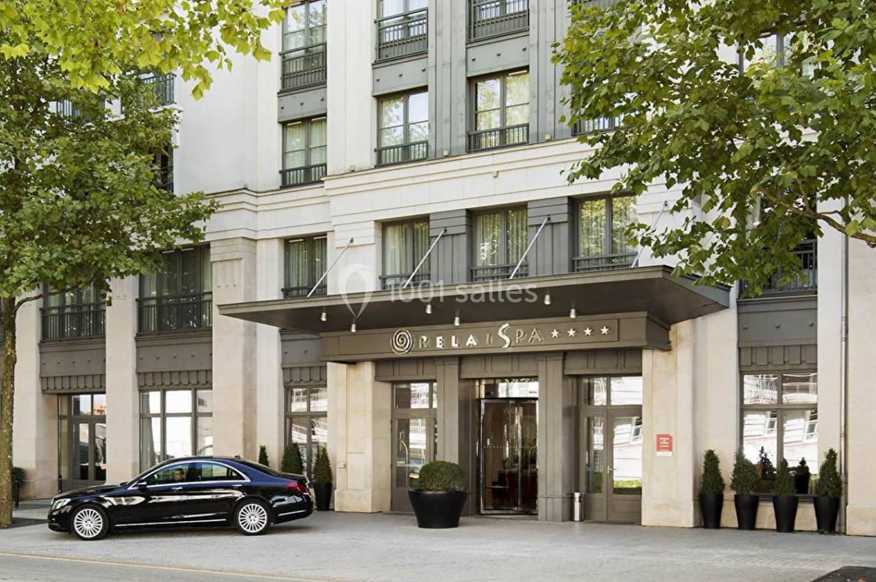 Façade d'un hôtel moderne avec entrée vitrée, enseigne ’Meliá Spa’ et une voiture noire stationnée devant.