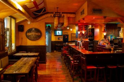 Façade d'un pub irlandais avec enseignes lumineuses vertes et jaunes, devant un bâtiment en pierre.