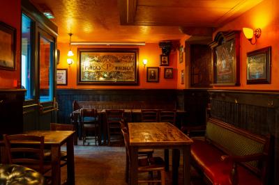 Façade d'un pub irlandais avec enseignes lumineuses vertes et jaunes, devant un bâtiment en pierre.