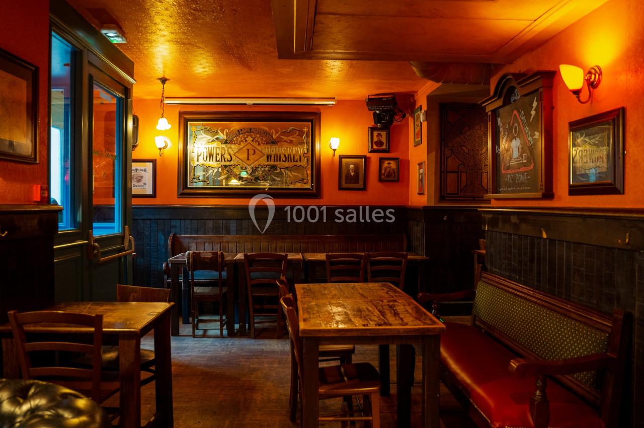 Intérieur d'un café chaleureux avec murs orange, mobilier en bois, banquette et éclairage tamisé.