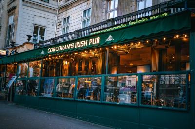 Façade d'un pub irlandais avec enseignes lumineuses vertes et jaunes, devant un bâtiment en pierre.