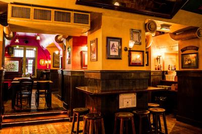 Façade d'un pub irlandais avec enseigne lumineuse verte et bâtiment en pierre en arrière-plan.