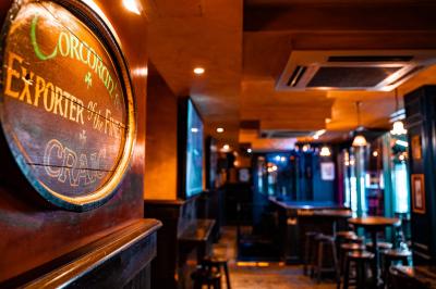 Façade d'un pub irlandais avec enseigne lumineuse verte et bâtiment en pierre en arrière-plan.