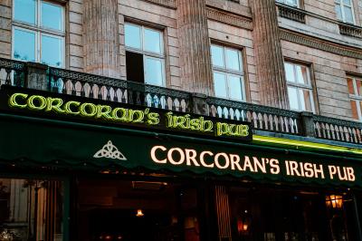 Façade d'un pub irlandais avec enseigne lumineuse verte et bâtiment en pierre en arrière-plan.