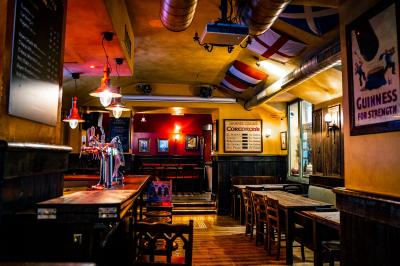 Façade d'un pub irlandais avec enseigne lumineuse verte et bâtiment en pierre en arrière-plan.