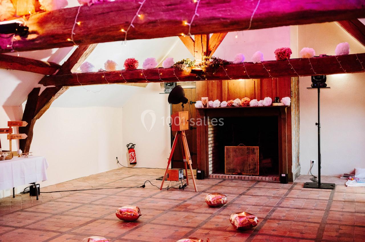Salle décorée avec des guirlandes lumineuses et des pompons colorés, avec une cheminée et un appareil photo vintage.