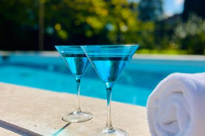 Deux verres de cocktail bleu posés sur le bord d'une piscine, avec une serviette blanche enroulée à côté.