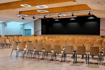 Bâtiment moderne entouré d'espaces verts, avec une aire de jeux pour enfants et un parking à proximité.