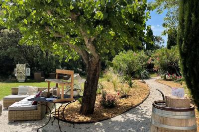 Cour d'une maison en pierre éclairée la nuit, avec arbres, mobilier de jardin et chemin bordé de lampes.