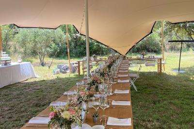 Cour d'une maison en pierre éclairée la nuit, avec arbres, mobilier de jardin et chemin bordé de lampes.