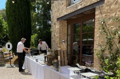 Cour d'une maison en pierre éclairée la nuit, avec arbres, mobilier de jardin et chemin bordé de lampes.