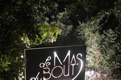 Cour d'une maison en pierre éclairée la nuit, avec arbres, mobilier de jardin et chemin bordé de lampes.