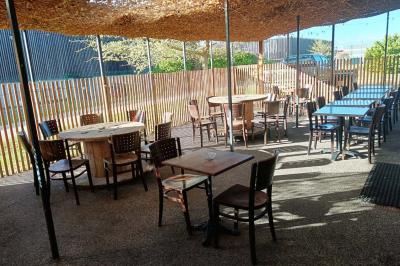 Salle de restaurant avec tables et chaises en bois, éclairage tamisé et décoration murale à motifs rouges.