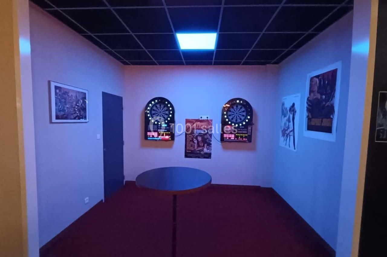 Salle avec deux cibles de fléchettes électroniques éclairées, entourées d'affiches sur des murs clairs.