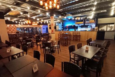 Salle de restaurant avec tables et chaises en bois, éclairage tamisé et décoration murale à motifs rouges.