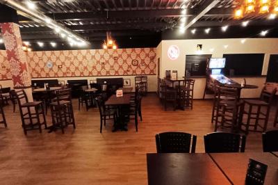 Salle de restaurant avec tables et chaises en bois, éclairage tamisé et décoration murale à motifs rouges.
