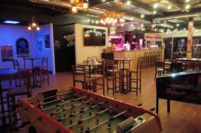 Salle de restaurant avec tables et chaises en bois, éclairage tamisé et décoration murale à motifs rouges.