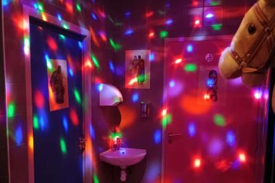 Salle de restaurant avec tables et chaises en bois, éclairage tamisé et décoration murale à motifs rouges.