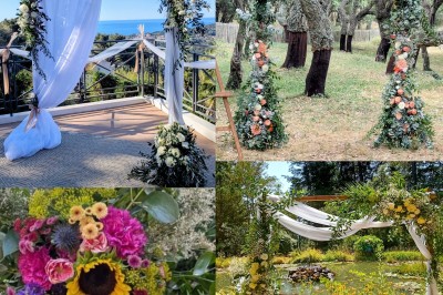 Allée centrale blanche menant à une arche de mariage décorée de fleurs, entourée de chaises blanches en extérieur.
