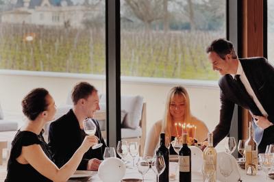 Quatre personnes regardent un coucher de soleil aux teintes orange et violet depuis une terrasse surplombant des vignes.