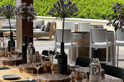 Quatre personnes regardent un coucher de soleil aux teintes orange et violet depuis une terrasse surplombant des vignes.