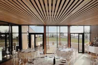 Quatre personnes regardent un coucher de soleil aux teintes orange et violet depuis une terrasse surplombant des vignes.