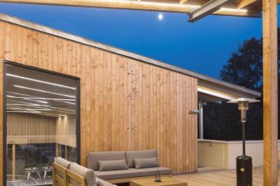 Quatre personnes regardent un coucher de soleil aux teintes orange et violet depuis une terrasse surplombant des vignes.