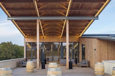 Quatre personnes regardent un coucher de soleil aux teintes orange et violet depuis une terrasse surplombant des vignes.