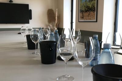 Façade d'un bâtiment clair avec une terrasse aménagée, un grand arbre et un ciel bleu en arrière-plan.