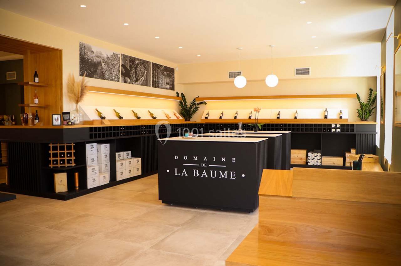 Intérieur d'une cave à vin moderne avec comptoir central, étagères de bouteilles et éclairage chaleureux.