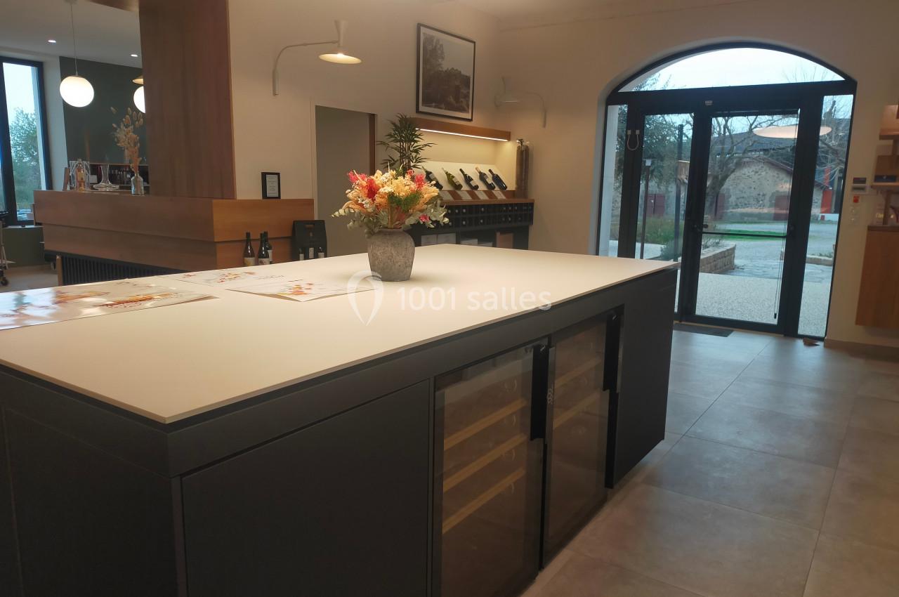 Comptoir moderne avec vase de fleurs, brochures posées, et vue sur une entrée vitrée donnant sur l'extérieur.