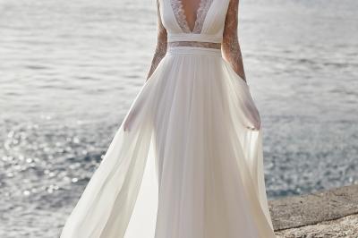 Femme portant une robe de mariée blanche avec un dos ouvert, posant dans un jardin fleuri.