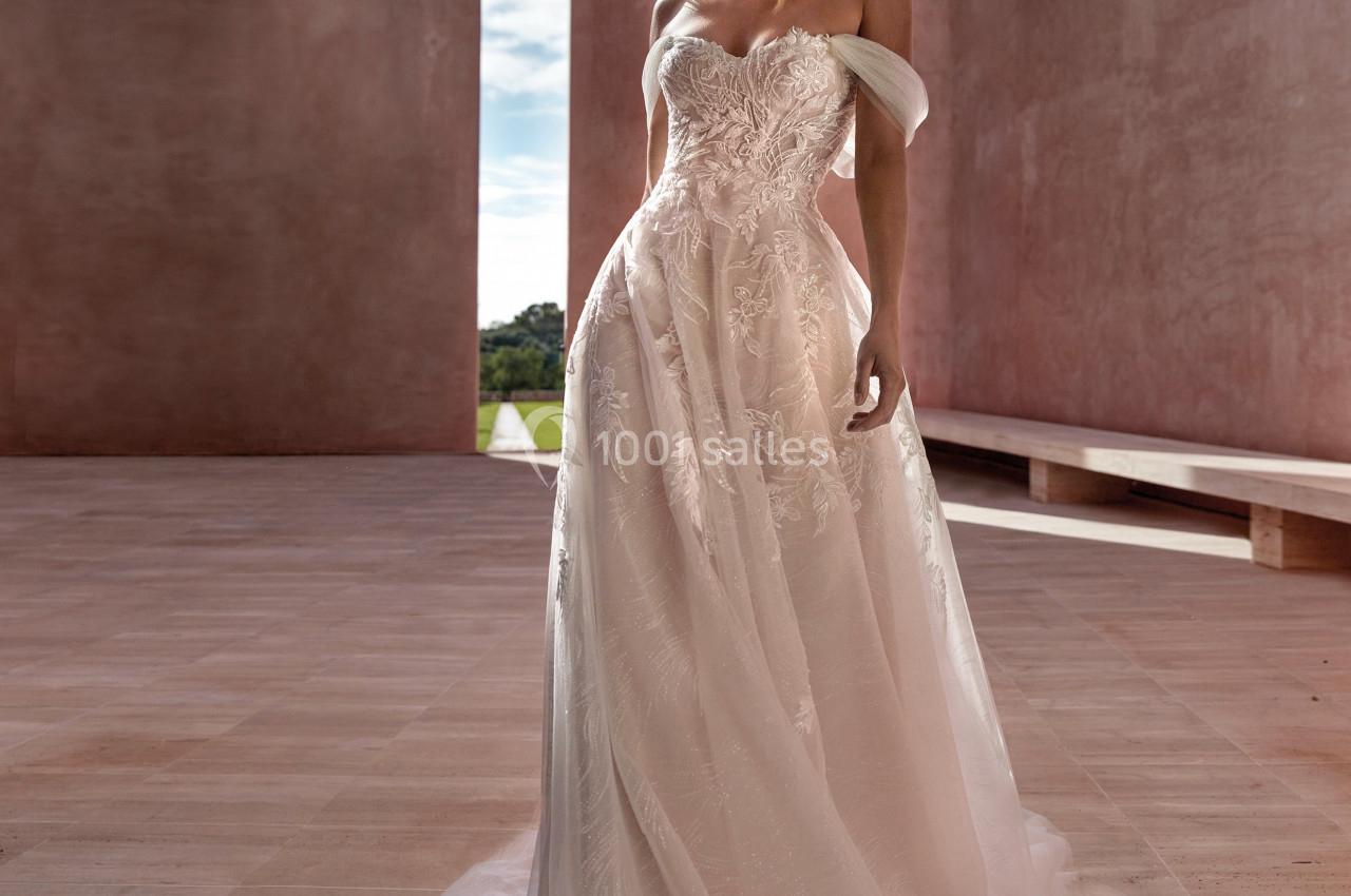 Femme portant une robe de mariée élégante dans un espace architectural minimaliste baigné de lumière naturelle.
