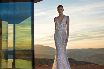 Femme portant une robe de mariée blanche avec un dos ouvert, posant dans un jardin fleuri.