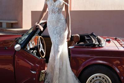 Femme portant une robe de mariée blanche avec un dos ouvert, posant dans un jardin fleuri.