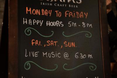 Façade d'un pub irlandais avec enseignes vertes, drapeau irlandais et arbres aux feuilles d'automne.