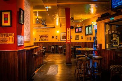 Façade d'un pub irlandais avec enseignes vertes, drapeau irlandais et arbres aux feuilles d'automne.