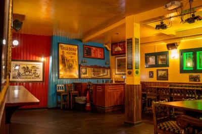 Façade d'un pub irlandais avec enseignes vertes, drapeau irlandais et arbres aux feuilles d'automne.