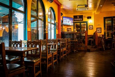 Façade d'un pub irlandais avec enseignes vertes, drapeau irlandais et arbres aux feuilles d'automne.