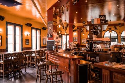 Façade d'un pub irlandais avec enseignes vertes, drapeau irlandais et arbres aux feuilles d'automne.