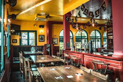 Façade d'un pub irlandais avec enseignes vertes, drapeau irlandais et arbres aux feuilles d'automne.