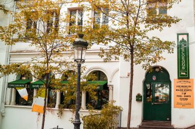 Façade d'un pub irlandais avec enseignes vertes, drapeau irlandais et arbres aux feuilles d'automne.