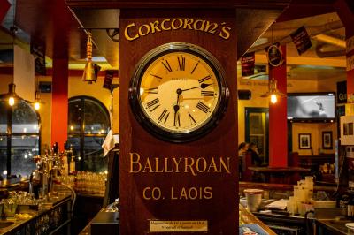 Façade d'un pub irlandais avec enseignes vertes, drapeau irlandais et arbres aux feuilles d'automne.