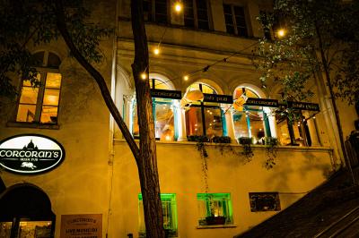 Façade d'un pub irlandais avec enseignes vertes, drapeau irlandais et arbres aux feuilles d'automne.