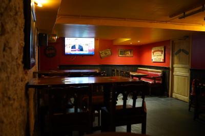 Intérieur d'un pub avec des tables en bois, des tabourets, un tableau noir et une ambiance tamisée.
