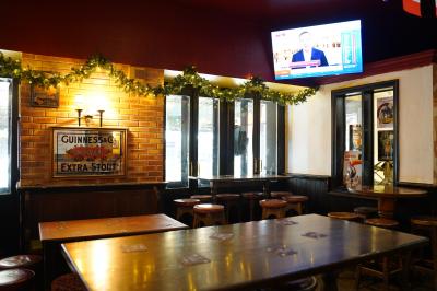 Intérieur d'un pub avec des tables en bois, des tabourets, un tableau noir et une ambiance tamisée.