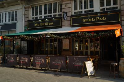 Intérieur d'un pub avec des tables en bois, des tabourets, un tableau noir et une ambiance tamisée.