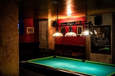 Intérieur d'un pub avec des tables en bois, des tabourets, un tableau noir et une ambiance tamisée.