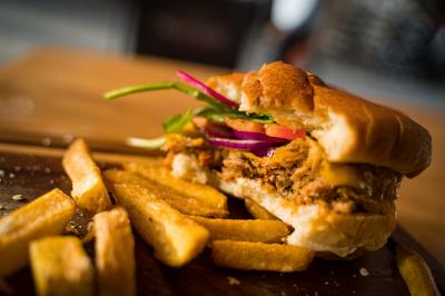 Intérieur d'un pub avec des tables en bois, des tabourets, un tableau noir et une ambiance tamisée.