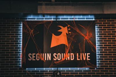 Tableau noir devant un établissement annonçant restauration, happy hour, musique live et club.